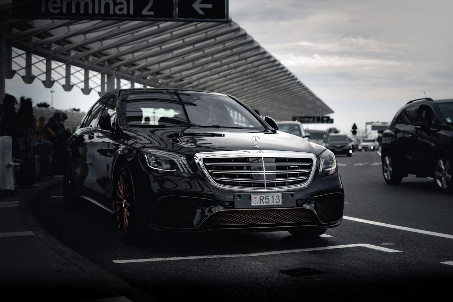 Zwarte Mercedes sedan geparkeerd onder een luifel bij de luchthaventerminal.