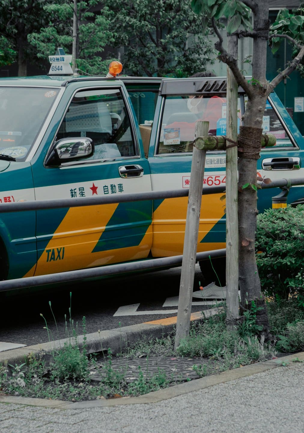 Een kleurrijke taxi staat geparkeerd naast een stoep met passagiers erin.