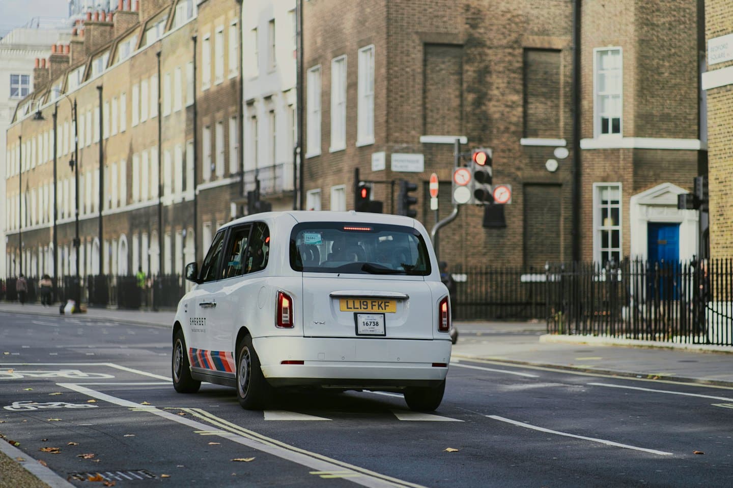 Moderne witte taxi rijdt weg op een stadsstraat.