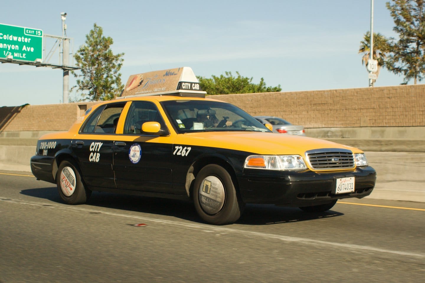 Een gele en zwarte taxi op de snelweg.